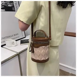 Detail of brown and beige cylindrical bucket bag featuring quilted texture and logo