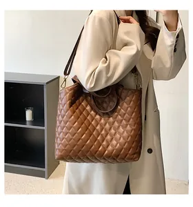 Detailed view of brown quilted tote bag with detachable strap shown on a white blazer