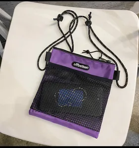 Detail view of purple nylon crossbody bag with black mesh pocket and logo