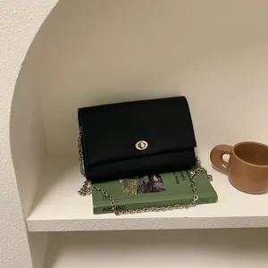 Borsa quadrata nera minimalista con trama litchi, chiusura a girello argento e tracolla a catena