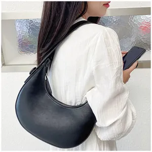 Side view of a black crescent shoulder bag worn by a model against a white wall