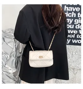 Rear view of a model wearing a cream quilted chain bag with gold metal hardware