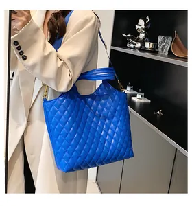 Close-up of electric blue quilted tote bag with golden hardware and leather straps