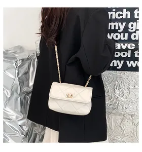 Detailed view of beige quilted square bag with gold metal twist lock and chain strap
