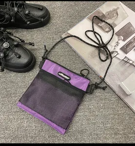 Detail of purple nylon crossbody bag with black mesh pocket and cord shoulder strap