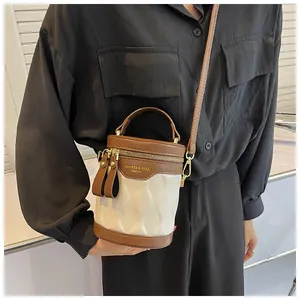 Detail of a mini bucket bag with wavy texture and brown leather trim on a model