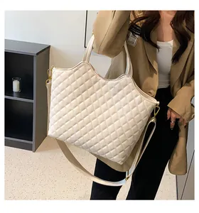 Detail of white quilted tote bag with golden metal hardware and adjustable shoulder strap