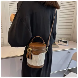 Model view showing the compact two-tone bucket bag worn crossbody with a long strap
