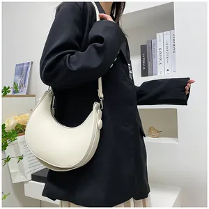 Side view of cream half-moon shoulder bag with smooth PU leather finish and silver hardware