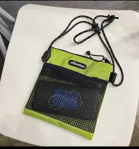 Detail of green nylon crossbody bag showing black mesh pocket and logo patch
