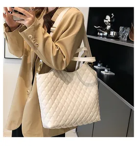 Detailed shot of white quilted tote bag with gold metal hooks and shoulder strap texture