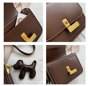 Detail view of dark brown PU crossbody bag with golden hardware and puppy charm