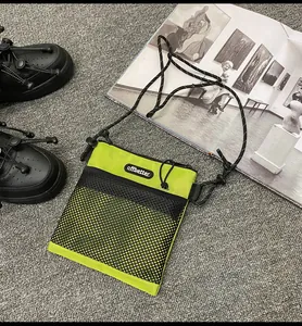 Close-up of neon green nylon crossbody bag with black mesh pocket and rope strap