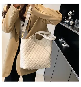 Close-up of a white quilted tote bag featuring a diamond pattern and wide fabric strap