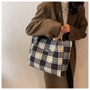 Dettaglio della borsa tote in lana a quadretti con etichetta in pelle e anelli dorati