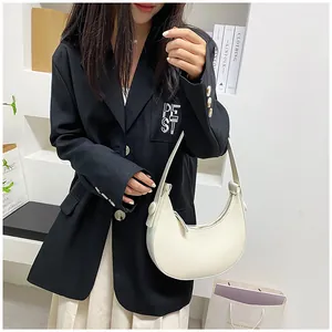 Detailed view of a creamy white crescent underarm bag styled with a black casual blazer
