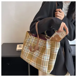 Dettaglio borsa tote a quadri con tracolla in pelle, catena oro e tasca cellulare