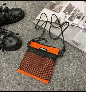 Close-up of vibrant orange nylon crossbody bag with black honeycomb mesh pocket and strap