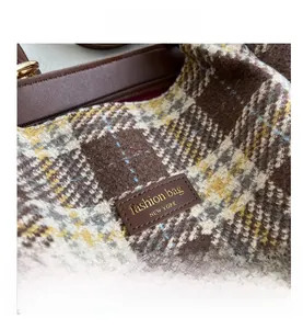 Dettaglio della borsa tote in tweed a quadri marroni con logo e cerniera superiore