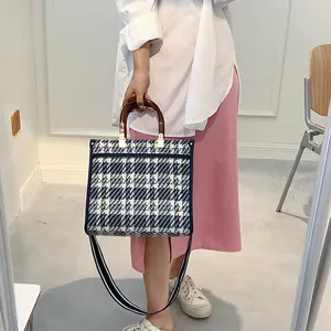 Detail of vintage plaid tweed tote bag with tortoiseshell handles and striped strap