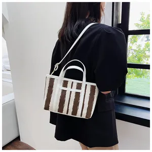 Dettaglio della borsa tote a righe indossata da modella che mostra dimensioni e stile