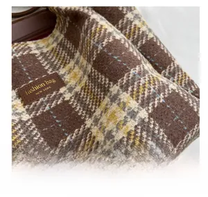 Dettaglio della trama in tweed a scacchi e dell'etichetta in pelle della borsa tote