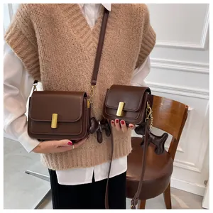 Detail view of retro brown leather crossbody bag set with golden hardware and dog charm