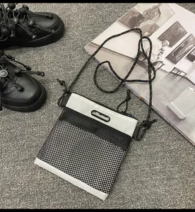 Detail of a nylon crossbody bag with black mesh stitching and adjustable rope strap