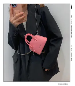 Dettaglio mini borsa a conchiglia rosa in pelle martellata con catena a sfere argento