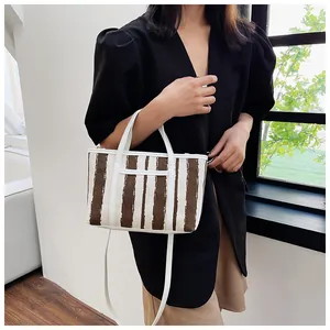 Dettaglio della borsa tote in tela con strisce marroni e finiture in pelle bianca