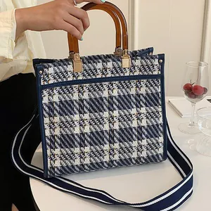 Detail of blue and white houndstooth woven tote with amber resin handle and wide strap