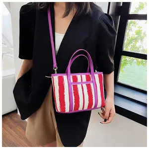 Borsa tote in tela a righe con finiture viola e tracolla indossata da una modella