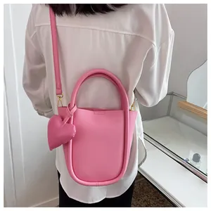 Borsa a secchiello rosa Barbie con ciondolo a cuore indossata a tracolla su camicia