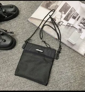 Detail view of black nylon mesh crossbody bag with reflective cord strap and logo