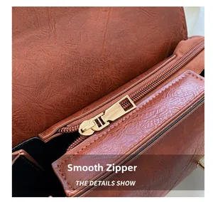 Close-up of smooth gold zipper and pebble leather texture on a brown shoulder bag