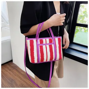 Borsa tote a righe rosse e bianche con manici viola indossata da una modella per lo stile