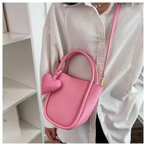 Dettaglio della borsa a secchiello semicircolare in pelle rosa chiaro con charm a cuore