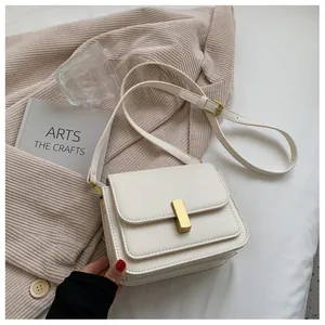 Detail of white vintage small square bag with gold buckle on soft fabric background