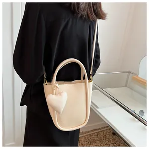 Elegante borsa a secchiello bianco crema con ciondolo a cuore indossata da una modella