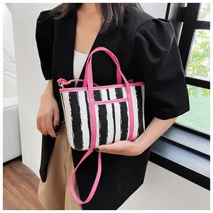 Dettaglio di una borsa tote a righe bianche e nere con eleganti manici rosa