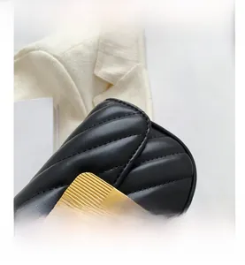 Détail d'un sac bandoulière en cuir noir matelassé avec fermoir rotatif en métal doré chic
