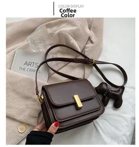 Detail of coffee brown PU leather shoulder bag with golden buckle and dog charm