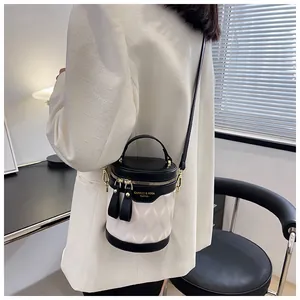 Detail of a black and white quilted cylinder bucket bag with gold zippers and metal hardware