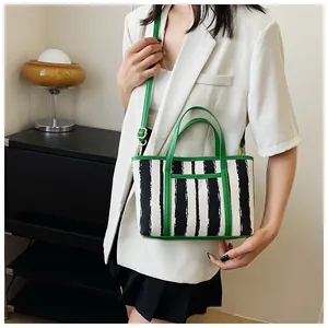 Dettaglio dei bordi in pelle verde e tela a righe bianche e nere della borsa tote