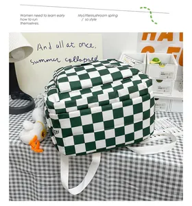 Dettaglio dello zaino a scacchi verdi con tasca frontale ed etichetta moda sulla scrivania