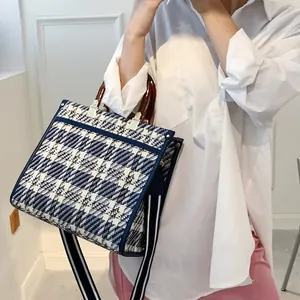 Detail of blue and white plaid tote bag with resin handles and striped strap