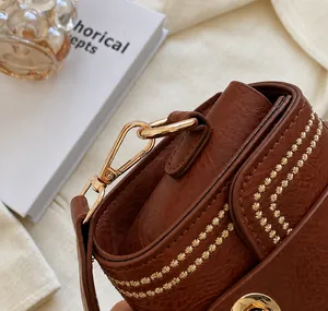 Macro shot of brown textured leather bag with star embroidery and gold metal hooks