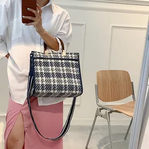 Detail of vintage plaid tote bag with round handles and striped wide shoulder strap