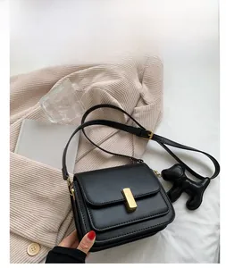 Detail of black leather square crossbody bag with gold buckle and cute puppy charm