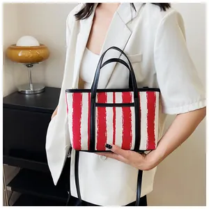Dettaglio della borsa tote in tela a righe rosse e bianche con finiture in pelle nera